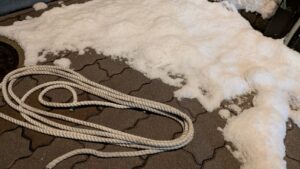 広島市東区牛田新町の坂道にて、スタックした車両を救助する便利屋万の店主。元消防士のロープワーク技術を使い、タイヤにロープを巻いて脱出をサポート。