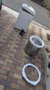 広島市東区の便利屋万にて、中古洗濯機の洗濯槽を取り外し、高圧洗浄機とブラシで徹底的に分解洗浄している様子。カビや汚れを除去して中古販売用に整備中。