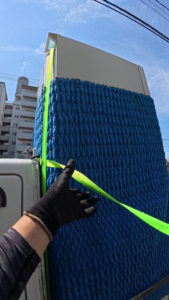 軽トラの荷台で、専用パットで保護した冷蔵庫をベルトで厳重に固定する様子