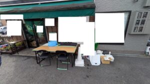 広島市安佐南区の法人様敷地内にて、倉庫から長机や椅子、カラーコーン、のぼり等を荷出しし、整然と並べて配置した便利屋 万の作業風景